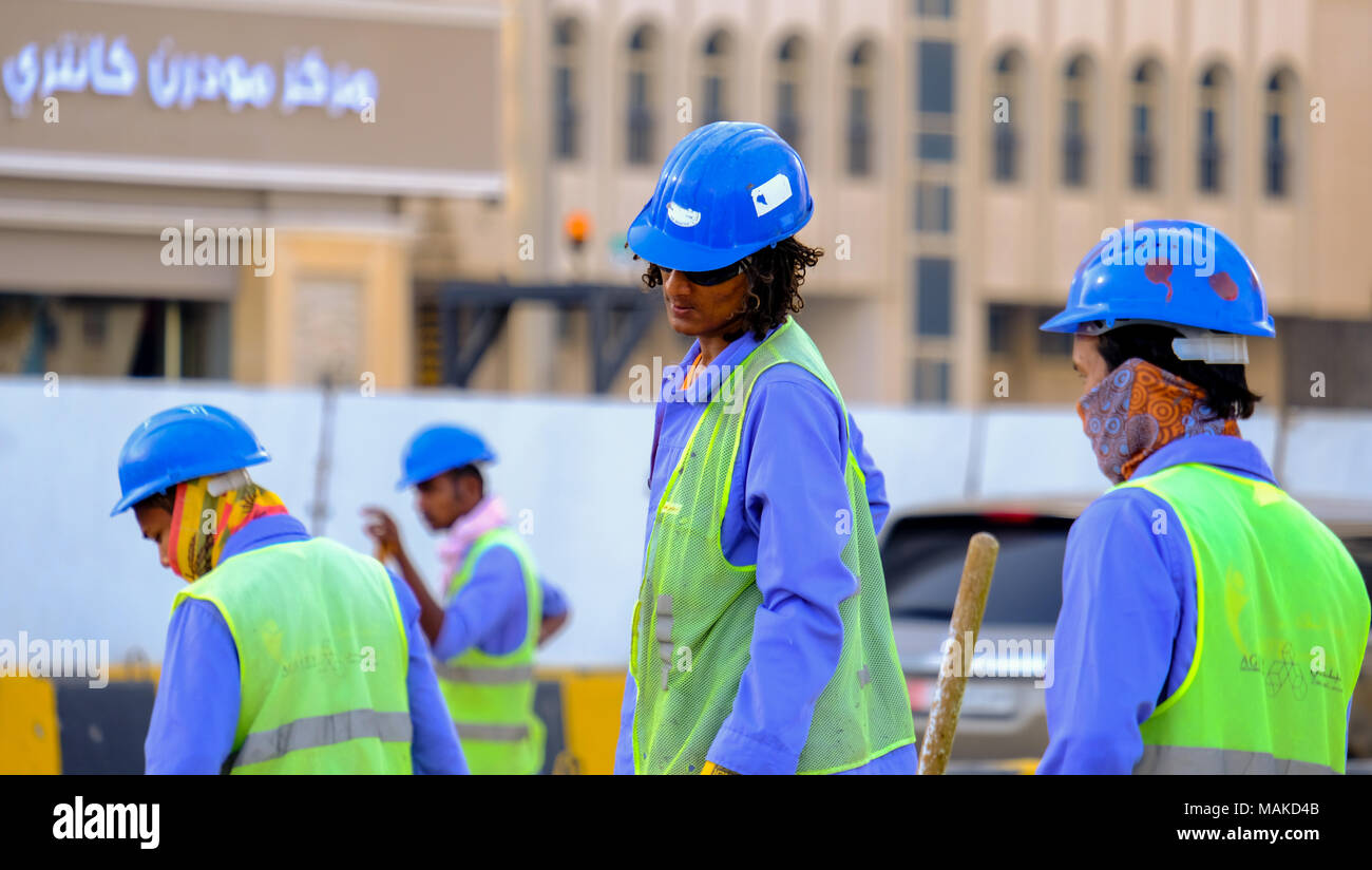 Group of Labours working at road side project warring blue uniform and blue helmets. In UAE most of the labours wear blue uniform also known as Dungaree. Stock Photo