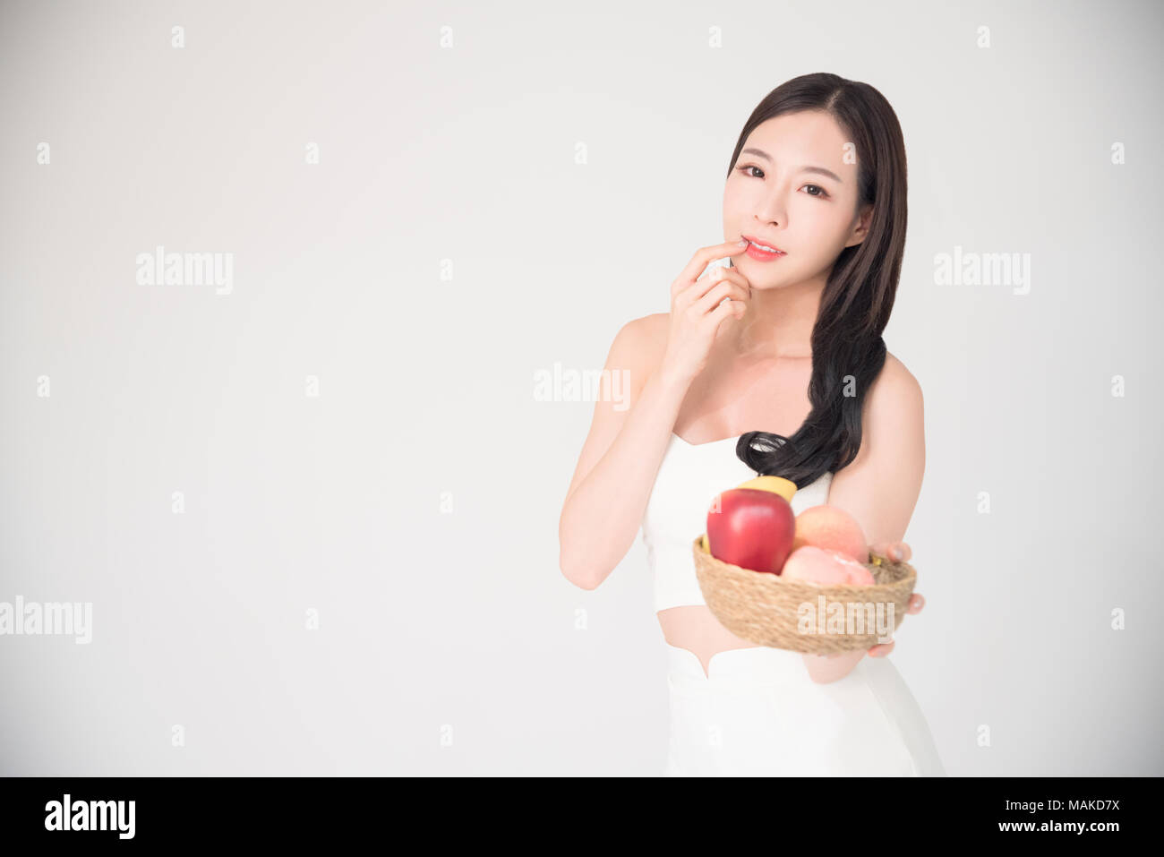 Healthy, Diet, Healthcare fruits or food Concept - Beautiful happy asian woman hold the bowl of fruits with smile isolated on white background. Stock Photo