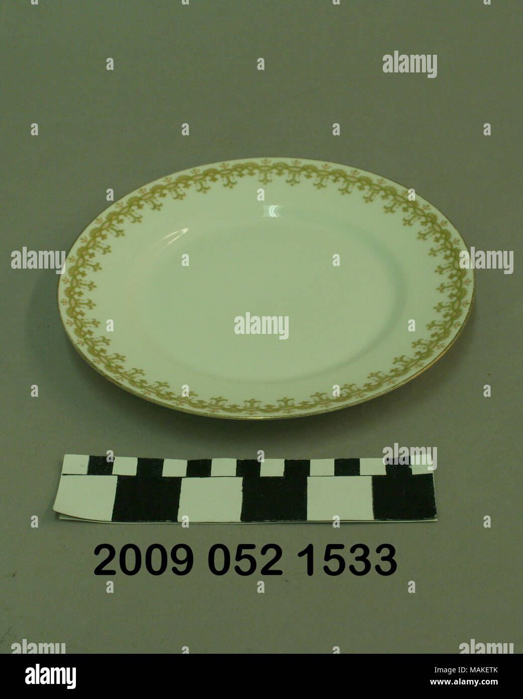 White ceramic salad size plate with green and red floral border. This was a grand prize winner from the 1904 World's Fair. Title: Small White Ceramic Plate With Floral Decorated Border  . after 1904. Stock Photo