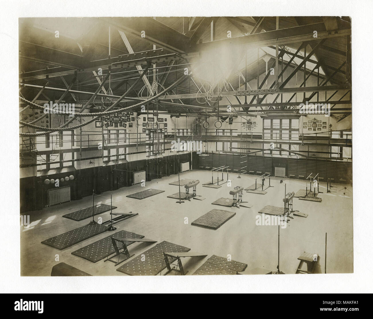 Horizontal photograph of the interior of a large gym. Equipment and mats are spread out on the floor. Title: A.G. Spalding and Bros. Model Gymnasium, Physical Culture Exhibit, Louisiana Purchase Exposition. (1904 Olympics). With overhead apparatus drawn up and out of the way.  . 1904. Stock Photo