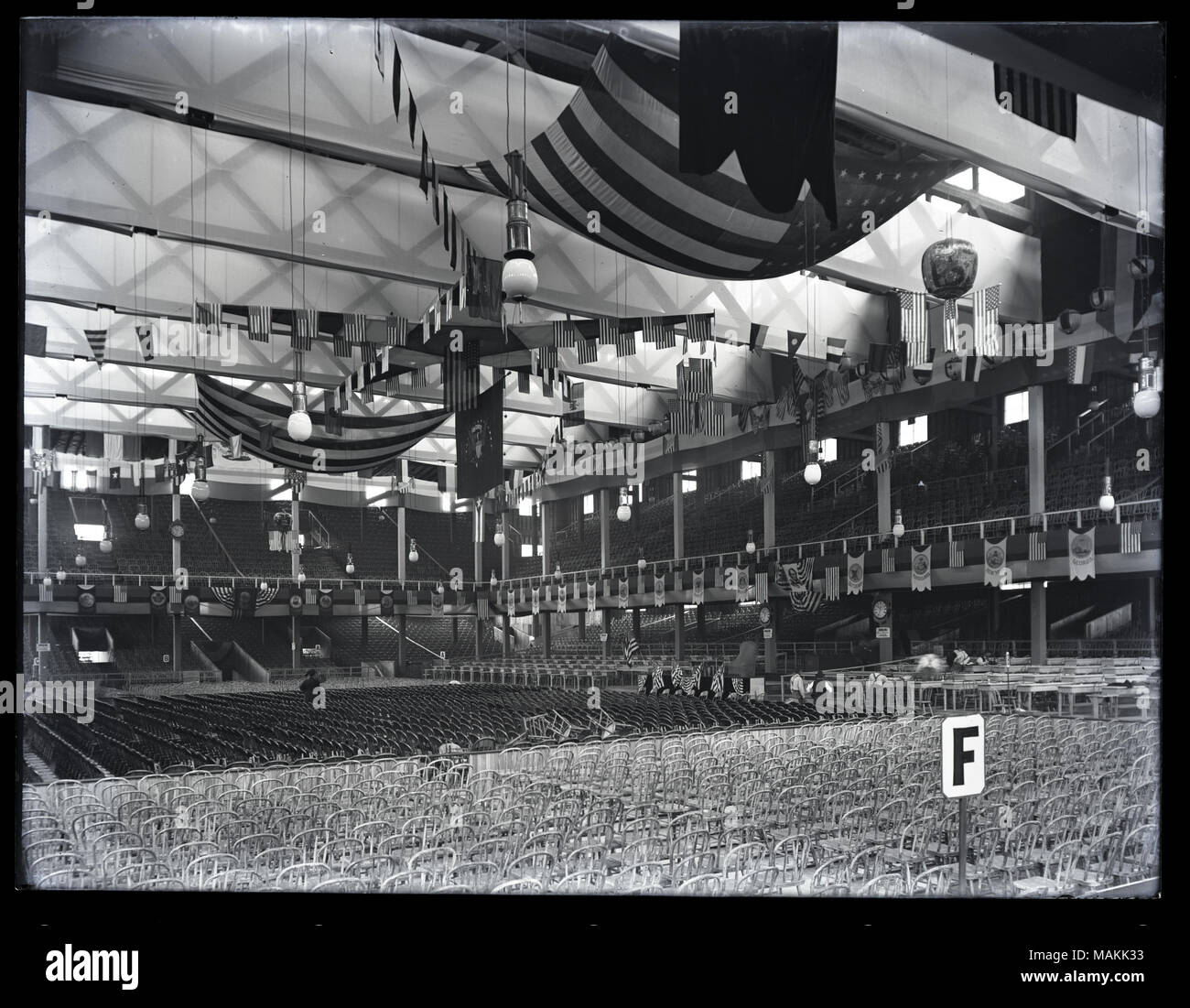 Horizontal, black and white photograph showing an interior view of the Republican convention hall, known as the 'Wigwam'. Many rows of chairs are crowded onto the floor and several levels of balconies. A variety of banners and flags hang from the ceiling. A sign in the lower right corner identifies section 'F'. The Wigwam was located on the grounds of City Hall, at the corner of 12th Street and Clark Avenue. The Republican National Convention was held on June 16-18, 1896. During the convention, William McKinley was nominated for president, and Garret A. Hobart was nominated for vice-president. Stock Photo