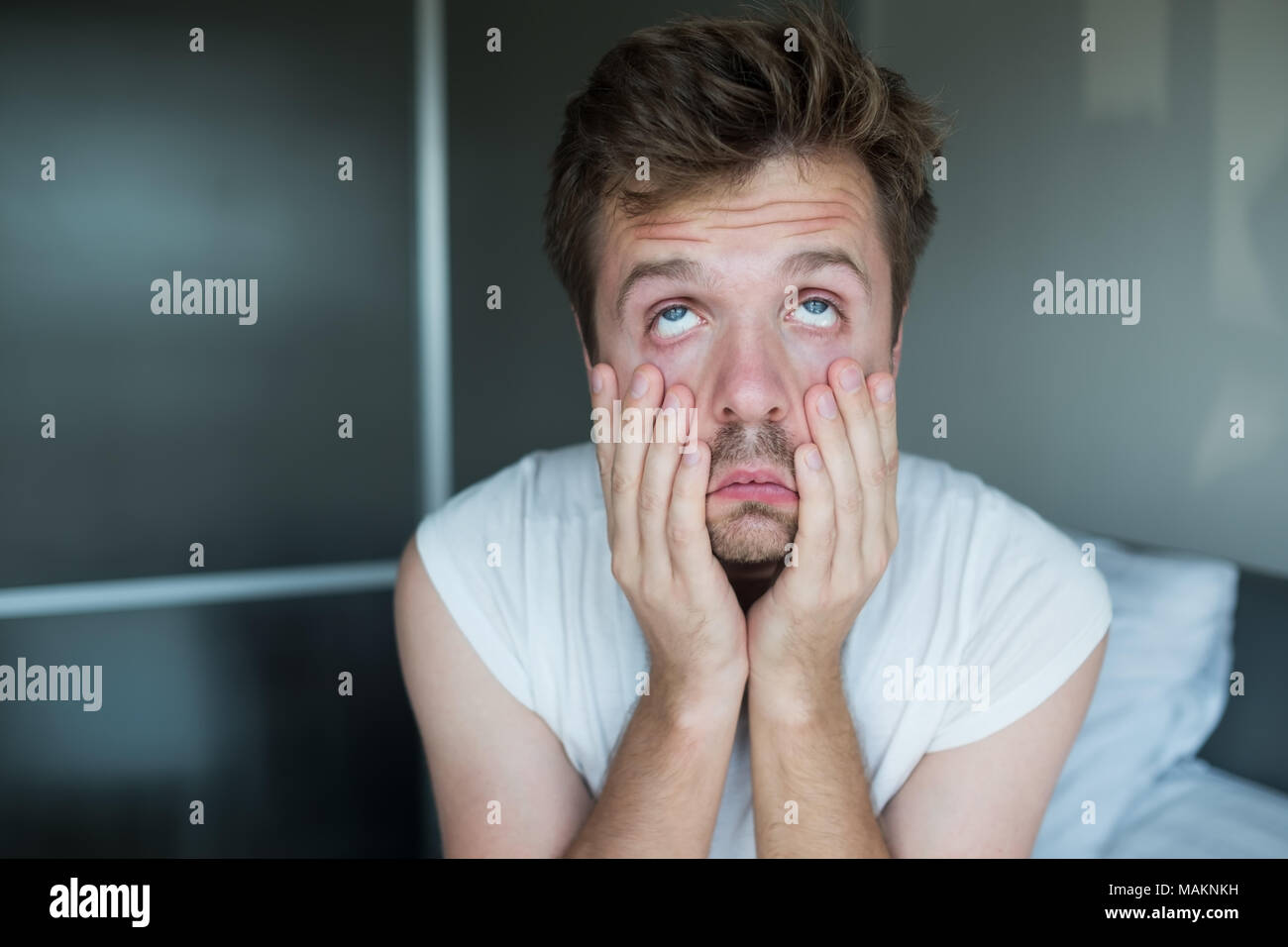 Tired caucasian man sitting on bed. Stock Photo