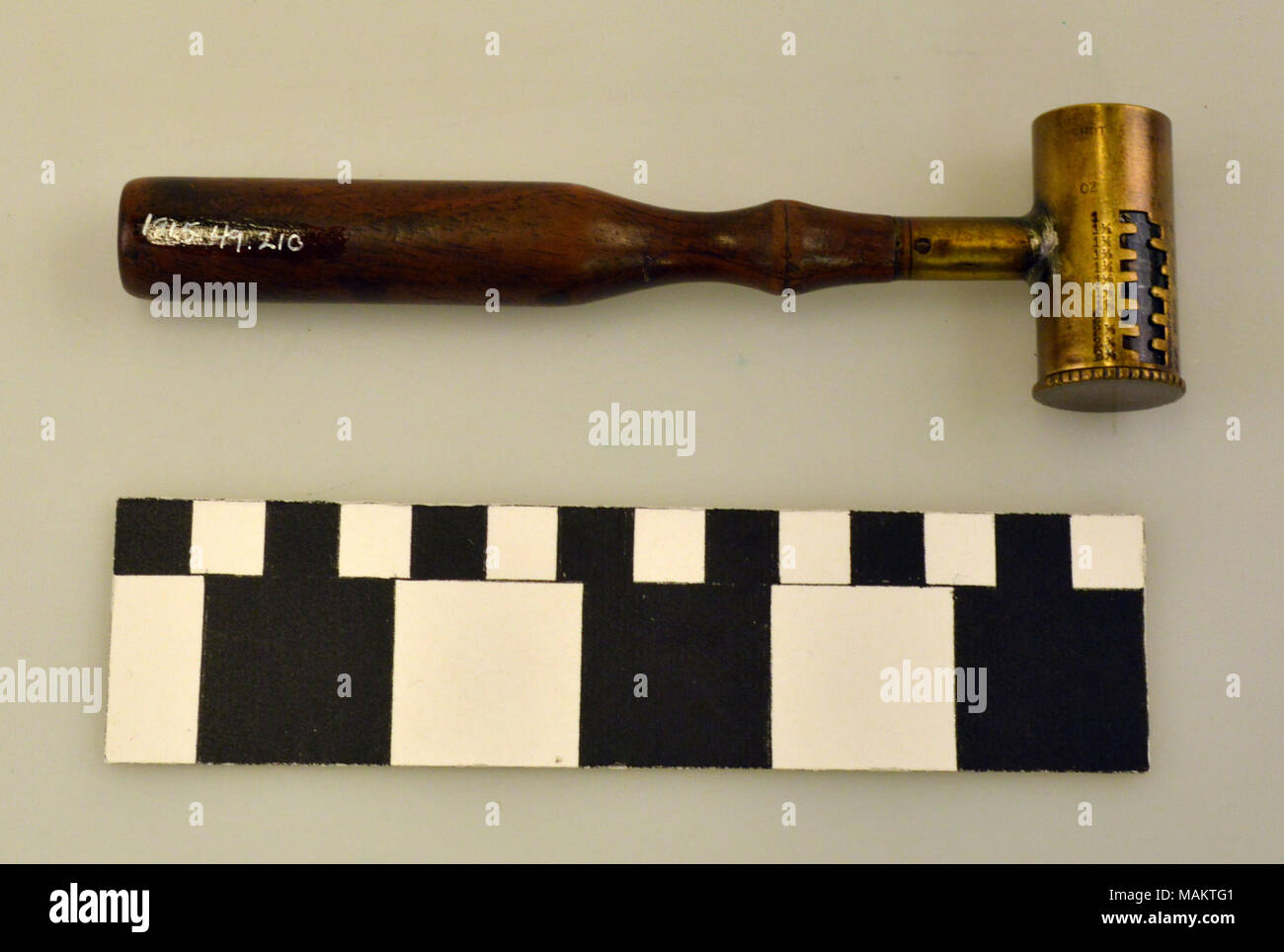Brass powder measure with graduated measurements in drams and ounces. Measure has a turned wood handle. Title: Wood Handled Brass Powder Measure  . between 1815 and 1915. Stock Photo