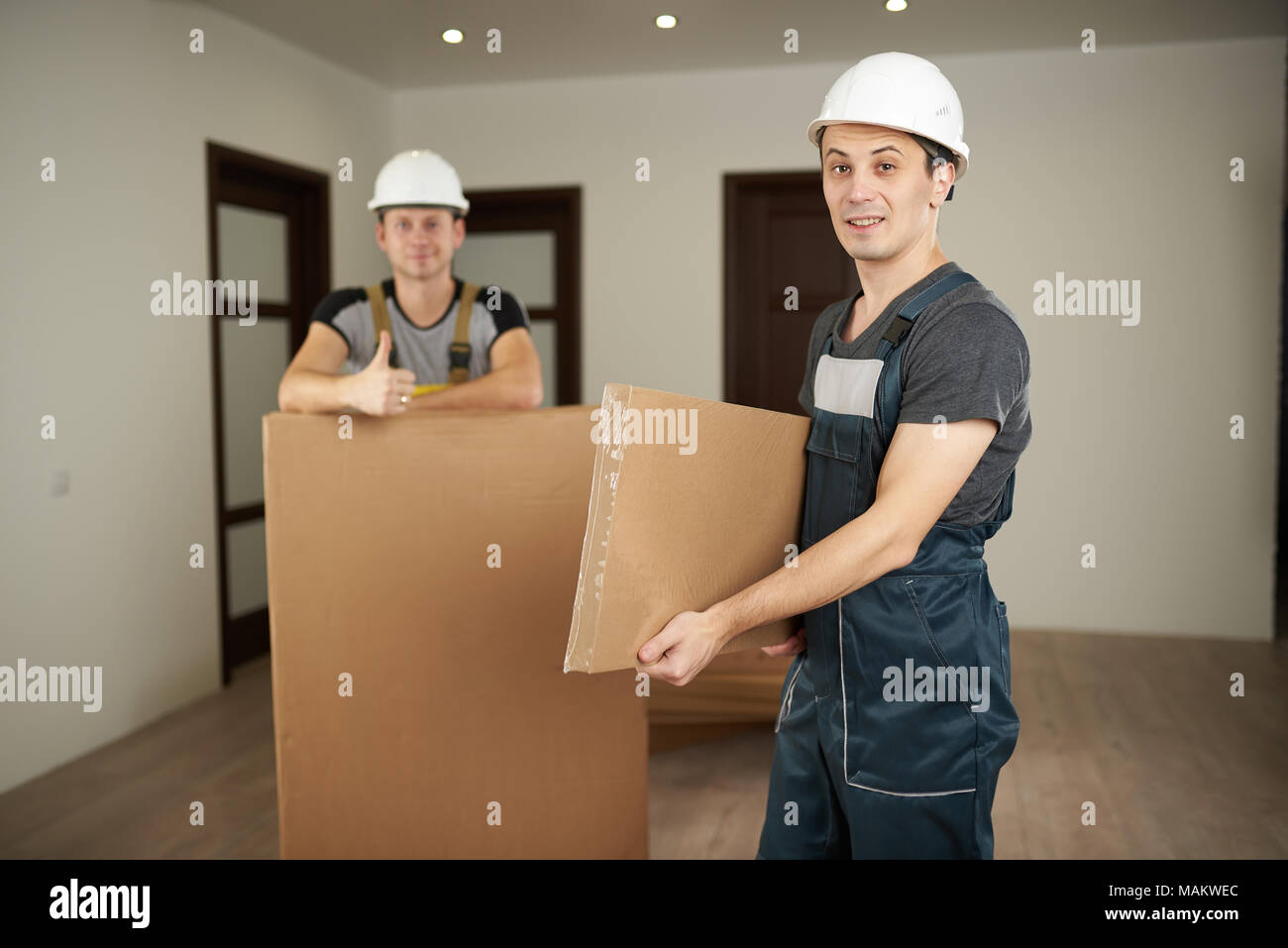 Furniture delivery theme. Two loaders move furniture in boxes into