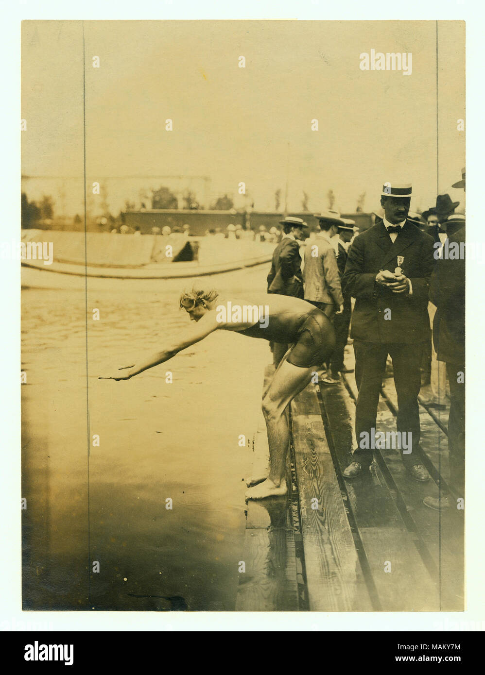 Vertical Photograph Of A Swimmer Poised To Begin Standing On The Edge Of The Dock With His Arms