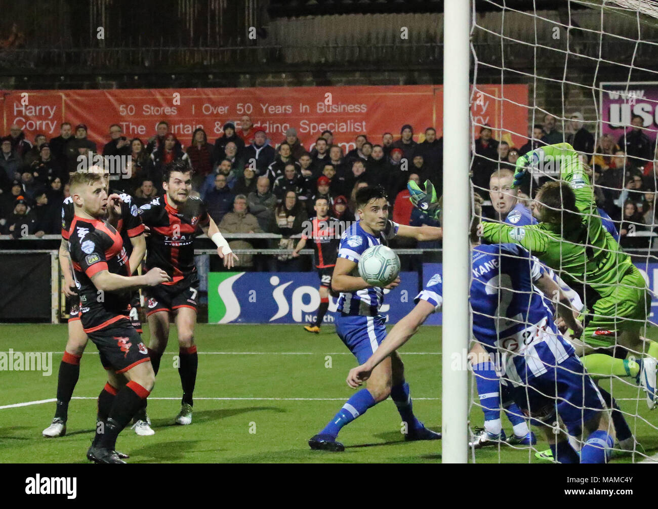 Seaview, Belfast, Northern Ireland, UK. 03 April 2018. Danske Bank Premiership - Crusaders 1 Coleraine 1. In tonight's top of the table clash at a packed Seaview, Crusaders drew 1-1 with Coleraine. The draw keeps Crusaders top of the league, two points ahead of Coleraine with four games to play. Coleraine goalkeeper Kris Johns kept out this effort from Philip Lowry but David Cushley (left - red/black) followed up to net the equaliser. Credit: David Hunter/Alamy Live News. Stock Photo