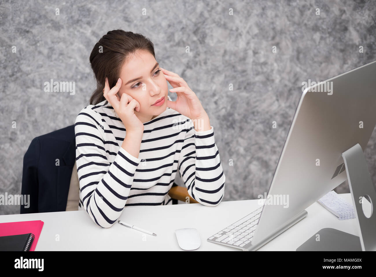 Beautiful young woman looking at a computer screen and thinking at the
