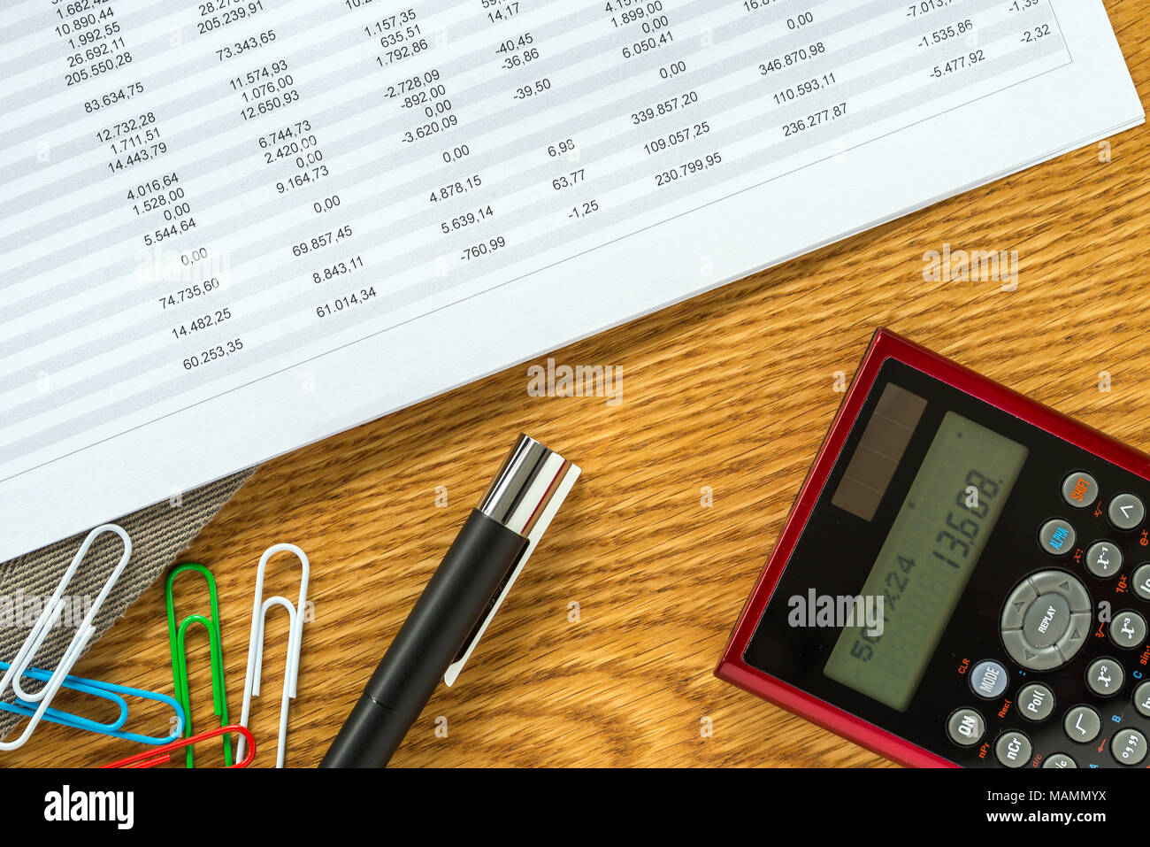 Close-up of accountant workspace as flat lay from above with paperwork and documents with numbers in tables, paper clips and calculator with wooden ba Stock Photo