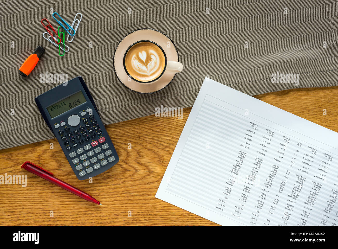 Accountant workspace as flat lay from above with paperwork and documents with numbers in tables and charts and calculator, marker pen, paper clips and Stock Photo