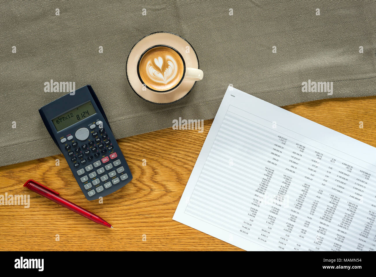 Accountant workspace as flat lay from above with paperwork and documents with numbers in tables and charts and calculator and coffee with wooden backg Stock Photo