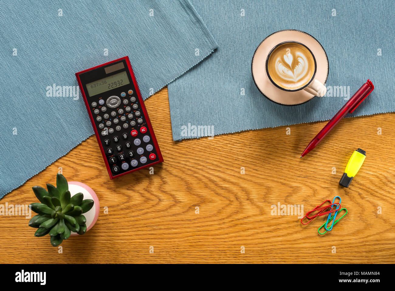 Accountant workspace as flat lay from above with numbers in calculator, plant, marker pen, paper clips and coffee with wooden background Stock Photo
