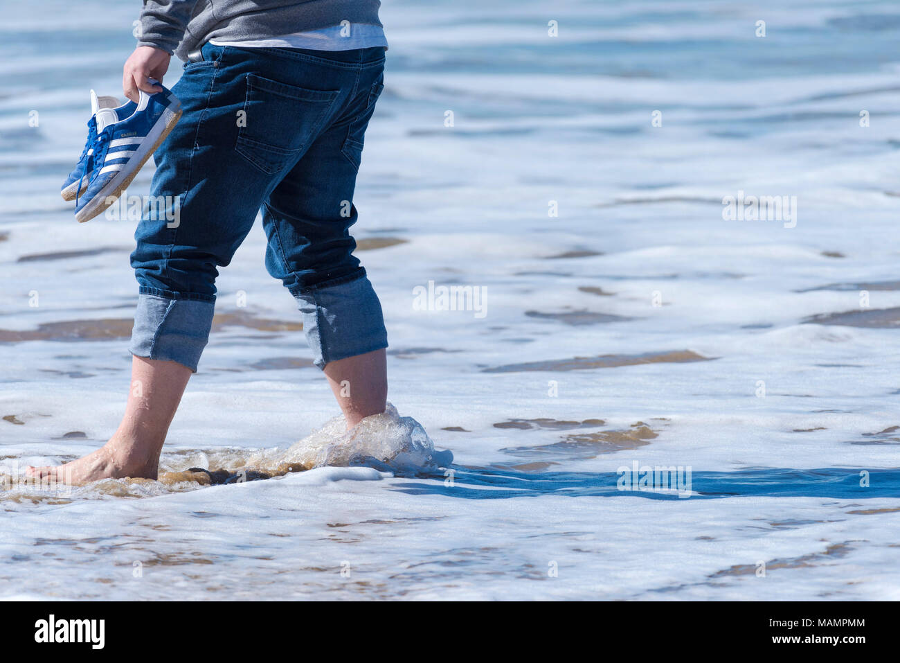 A holidaymaker paddling in the sea at Fistral Beach in Newquay Cornwall Stock Photo