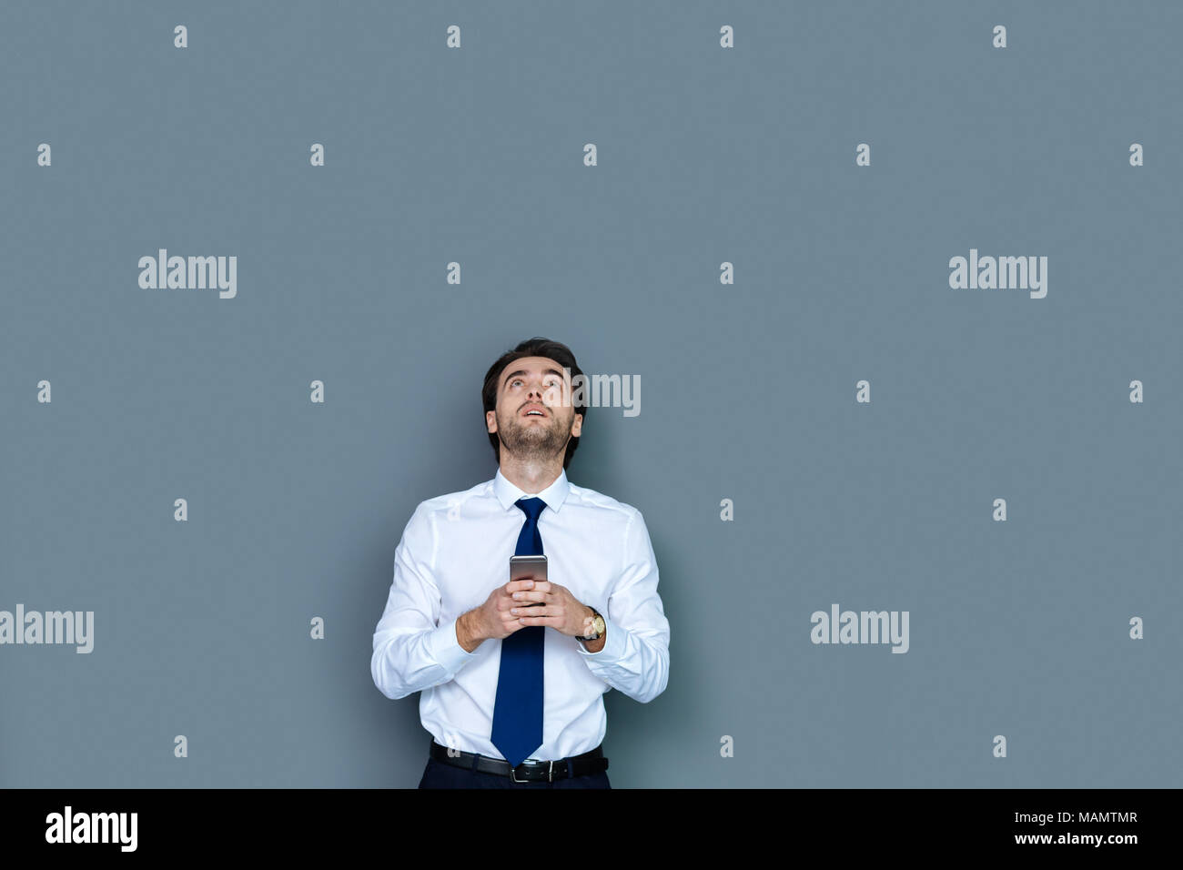 Serious confident businessman holding his gadget Stock Photo