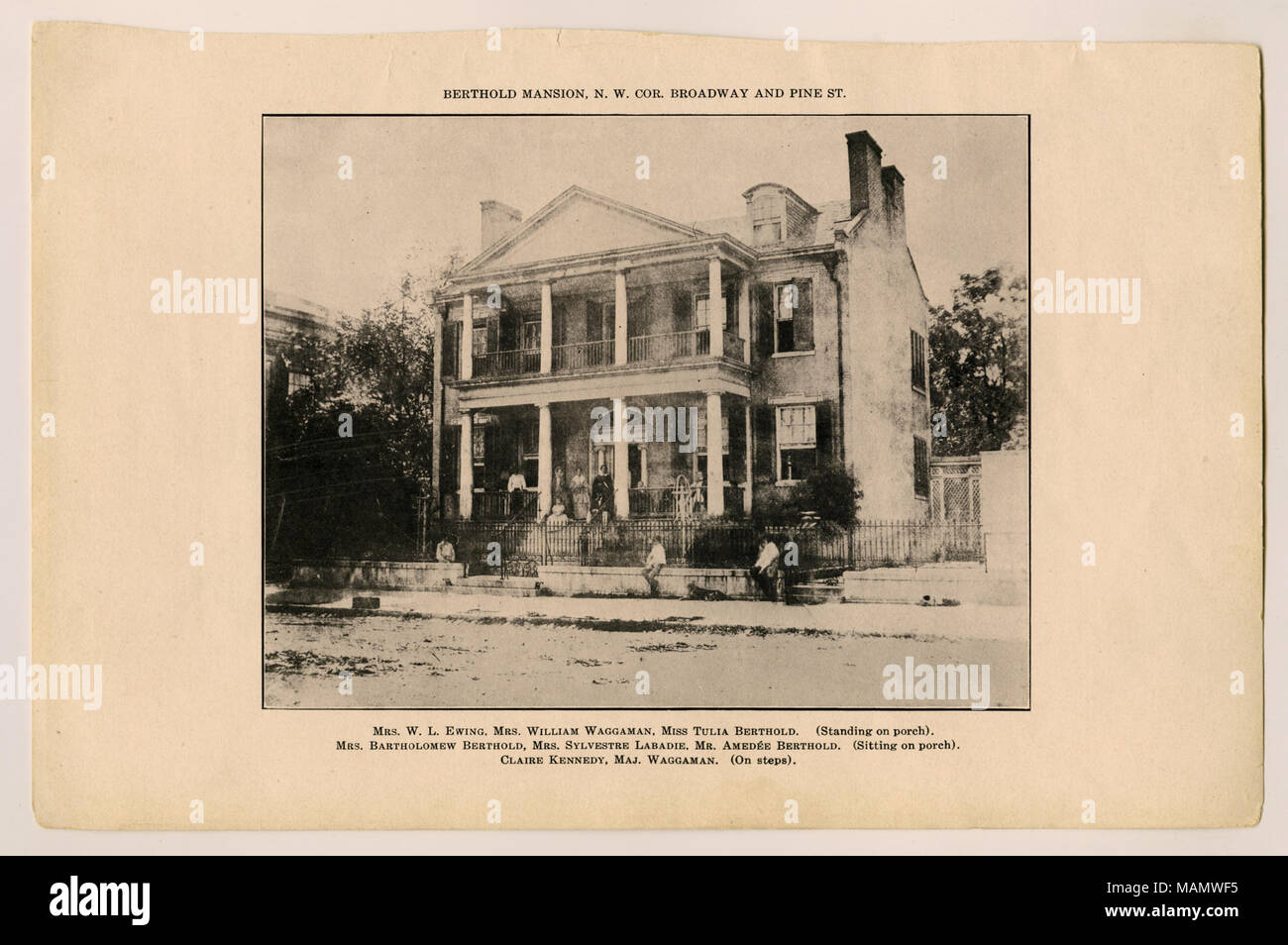 Horizontal, Black and white photograph of a two story brick residence. A wrought iron fence is in front of the structure and members of the household are pictured on the porch and steps of the residence. Caption above photo reads Berthold Mansion, N.W. Cor. Broadway and Pine St. Bottom Caption lists members in photo: Mrs. W.L. Ewing, Mrs. William Waggaman, Miss Tulia Bertholdd (Standing on porch) Mrs. Batholomew Berthold, Mrs. Sylvestre Labadie, Mr. Amedee Berthold (Sitting on porch) Claire Kennedy, Maj. Waggaman. (On steps) Title: Berthold Residence. Northwest corner Broadway and Pine Street. Stock Photo