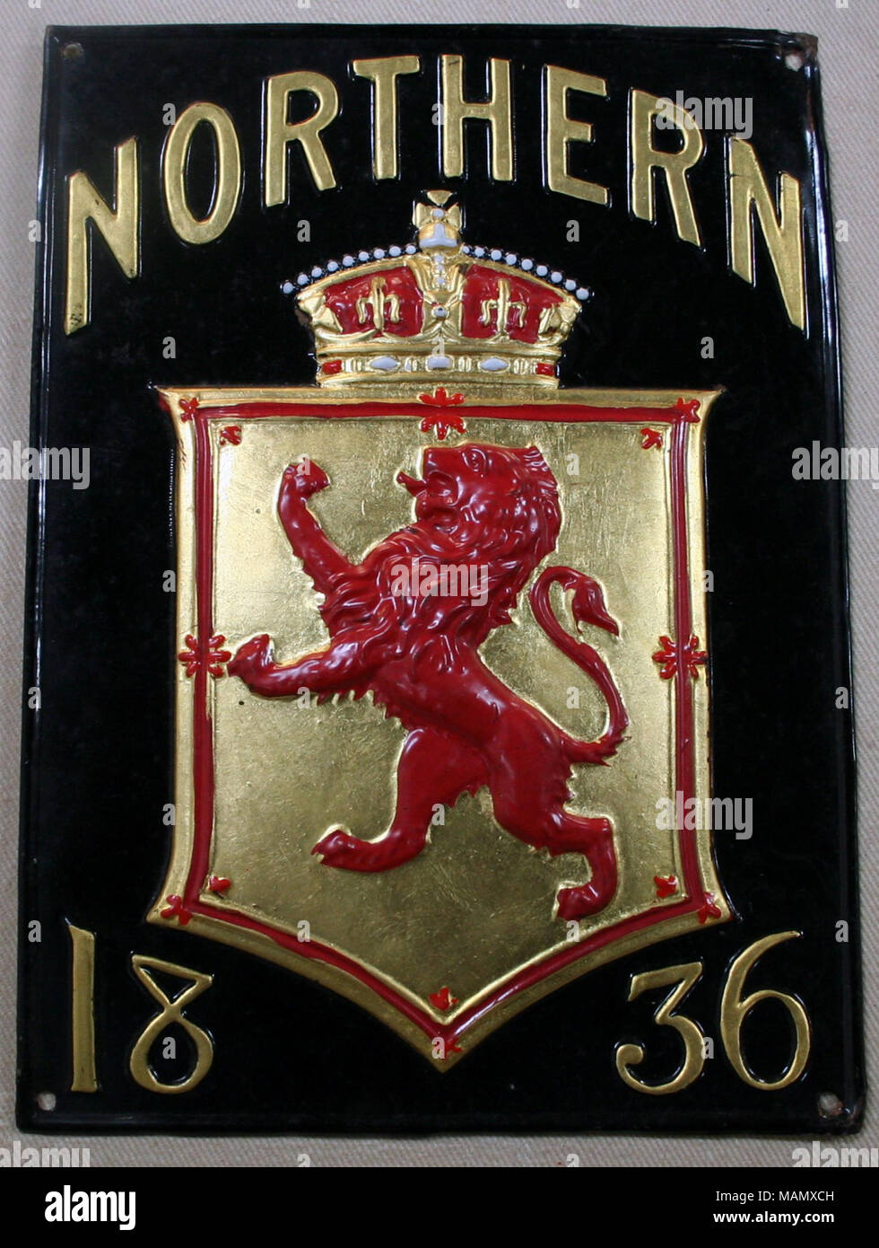Copper pressed fire mark for Northern Assurance Company, Limited in London, England showing raised rampant red lion on gold shield and crown above on rectangular mark Title: Fire mark for The Northern Assurance Company, Limited in London, England  . after 1836. Stock Photo