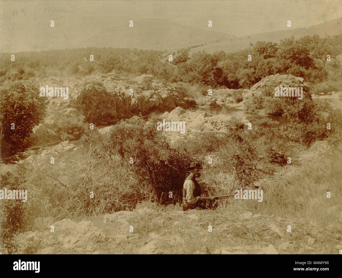 Title: Landscape near Fort Sill, including a man with a rifle and Mt. Scott in the distance.  . between circa 1890 and circa 1895. George A. Addison Stock Photo