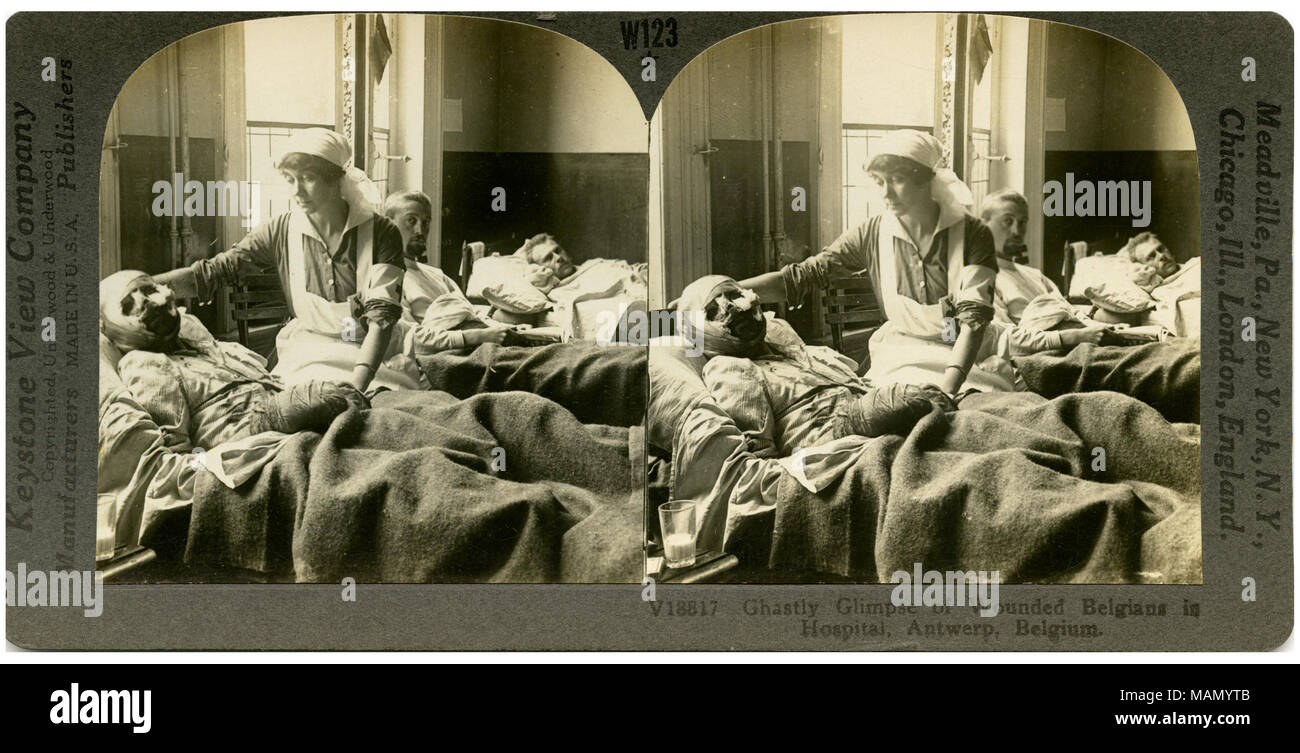 Horizontal, sepia stereocard showing three men in hospital beds and one nurse. The man in the foreground has his head and hands wrapped in bandages. Keystone Stereograph number V18817. The title reads: 'Ghastly Glimpse of Wounded Belgians in Hospital, Antwerp, Belgium.' Title: 'The Horror of War - Ghastly Glimpse of Wounded.'  . between circa 1914 and circa 1918. Keystone View Company Stock Photo