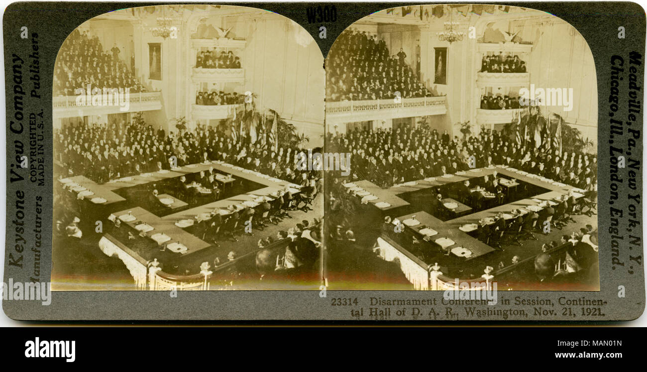 Horizontal, sepia stereocard showing a large room filled with delegates seated around tables arranged in a square. The upper galleries are also filled with people. Keystone Stereograph number 23314. The title reads: 'Disarmament Conference in Session, Continental Hall of D. A. R.. Washington, Nov. 21, 1921.' Title: 'Conference Delegate in Session, Continental Hall, Washington, D.C.'  . 21 November 1921. Keystone View Company Stock Photo