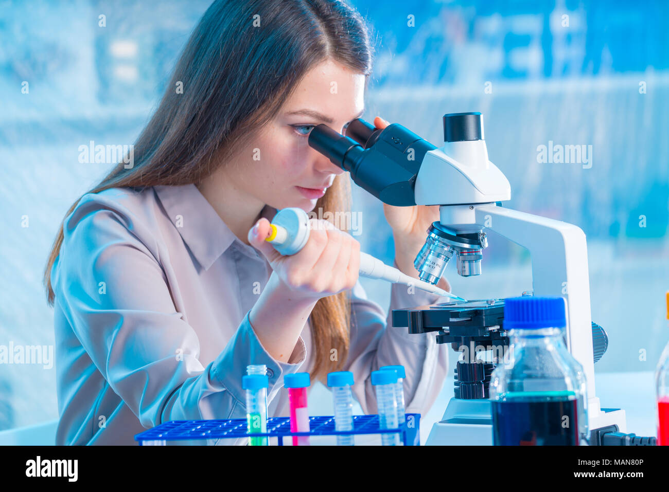 Young chemist in the laboratory. Scientist Using Microscope In Lab Stock Photo