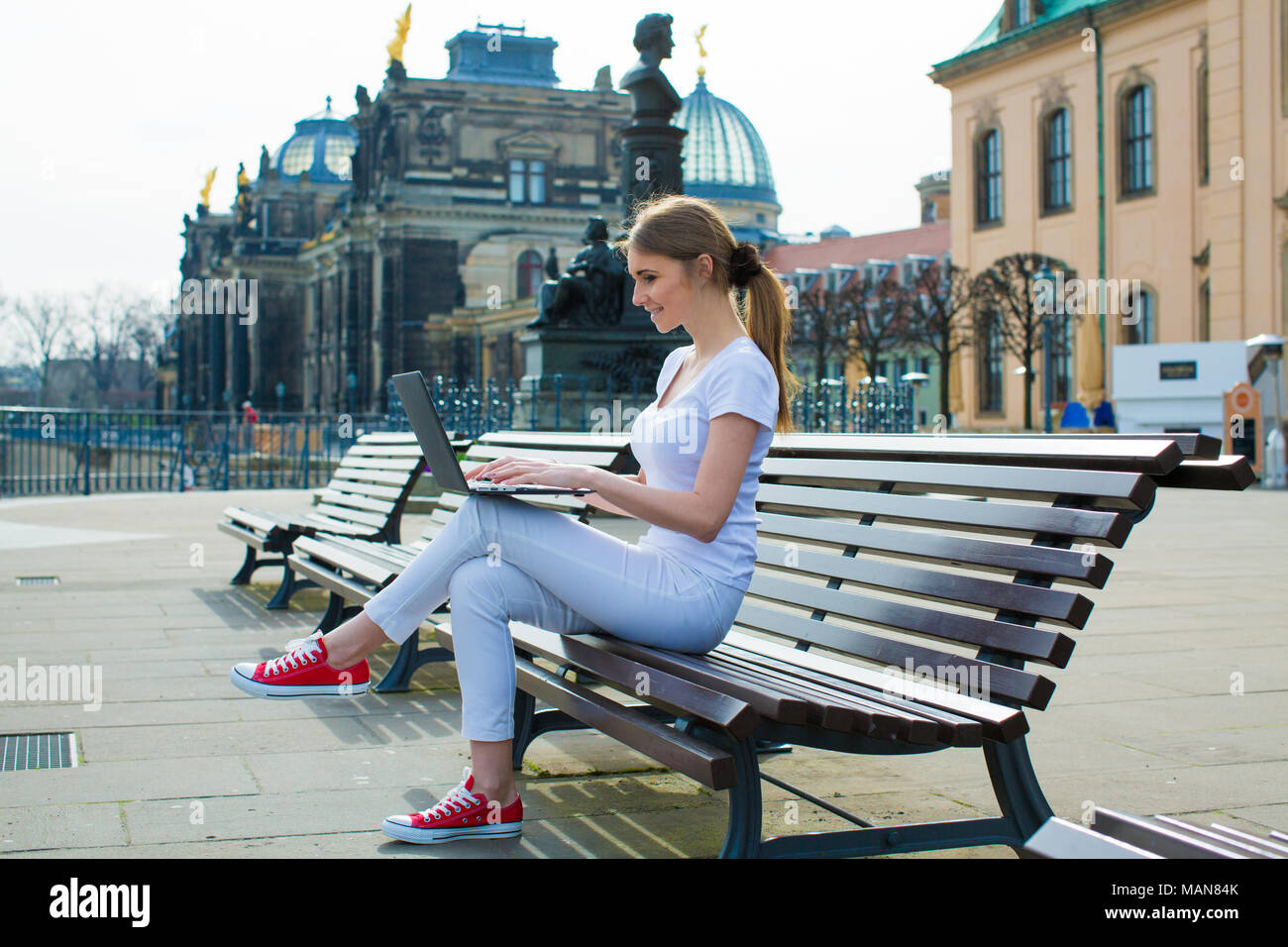 The girl in The Dresden sitting on the bench and writes in diary and laptop Stock Photo
