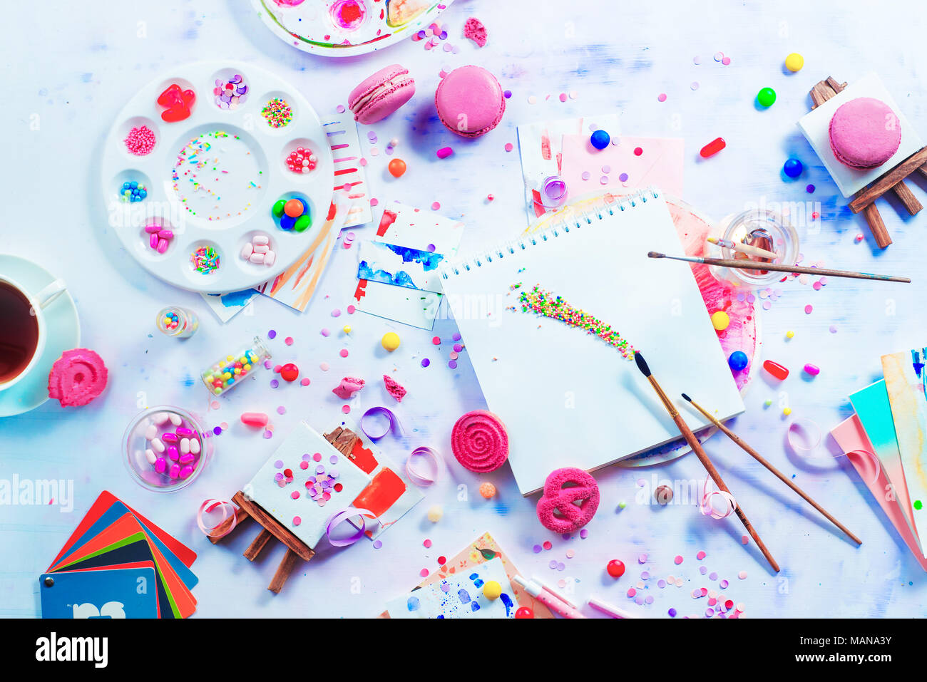Artist workplace colorful flat lay with sweets, candies and sprinkles. Painting a dessert with a watercolor pallet filled with hard candies. Party con Stock Photo