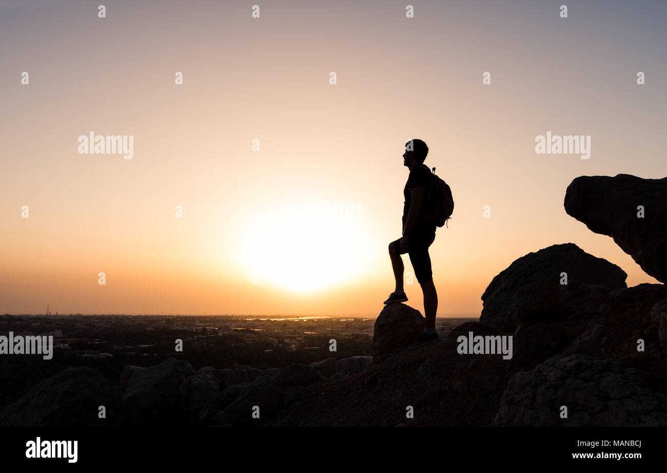 Hiker on the mountain top facing the sunset, silhouette shoot Stock Photo