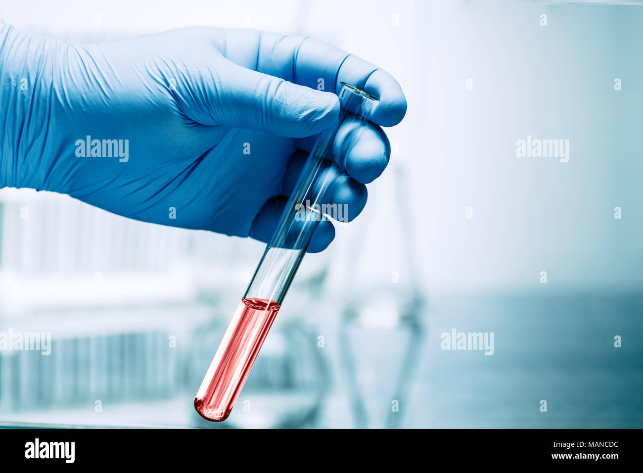 Hand in glove holding test tube on blurred background Stock Photo - Alamy