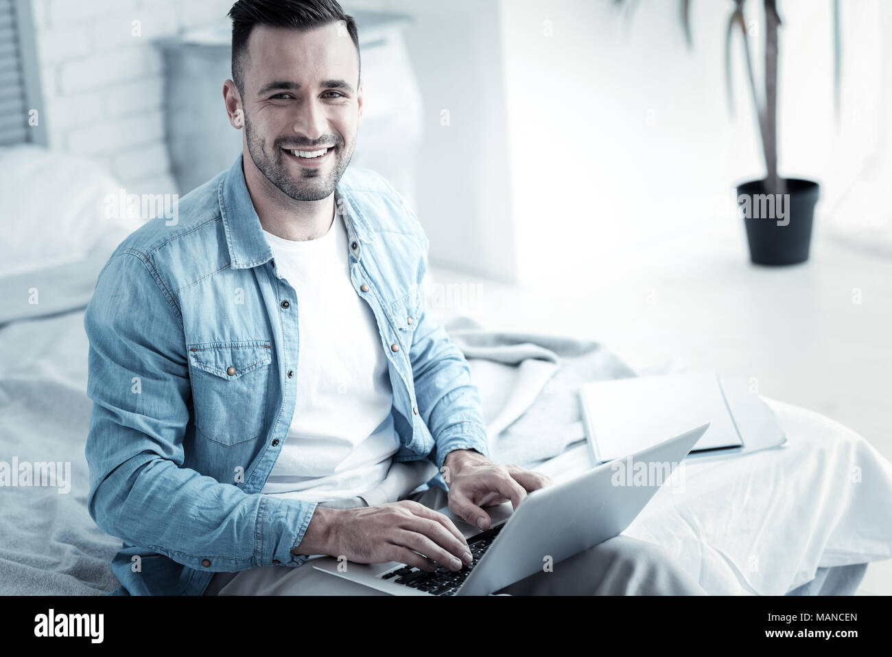 Delighted cheerful man using his laptop Stock Photo