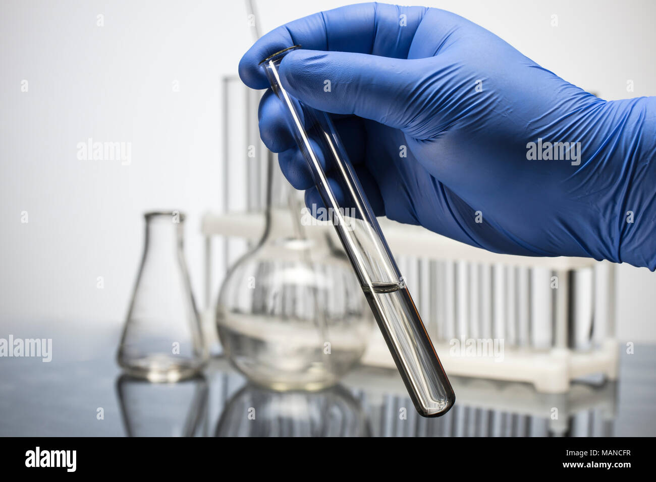 Hand in glove holding test tube on blurred background Stock Photo - Alamy