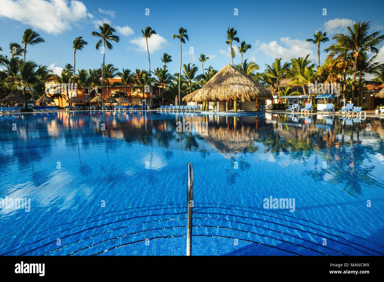 Tropical swimming pool and palm trees in luxury resort Stock Photo - Alamy