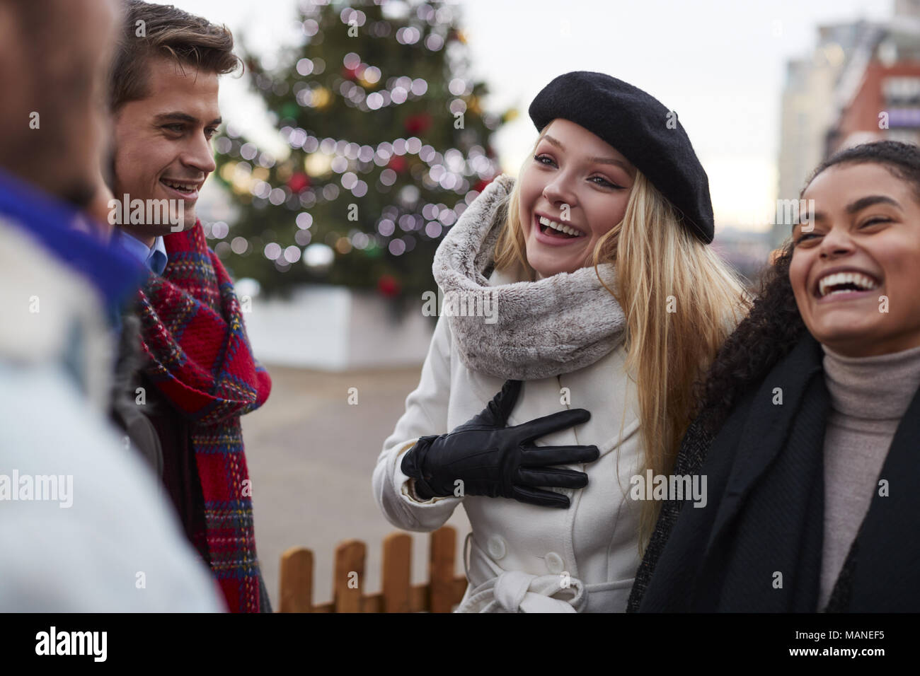Young Friends On Walk Standing By Christmas Tree Stock Photo