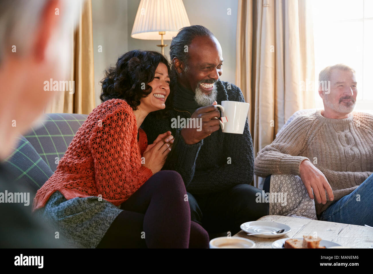 Middle Aged Couple Meeting Friends Around Table In Coffee Shop Stock Photo