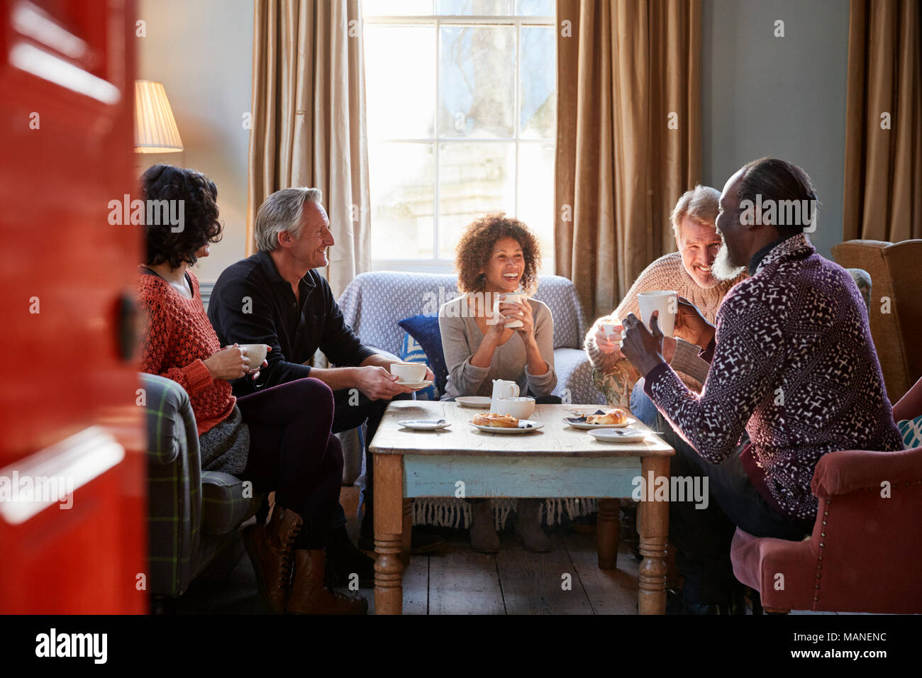 Group Of Middle Aged Friends Meeting Around Table In Coffee Shop Stock Photo