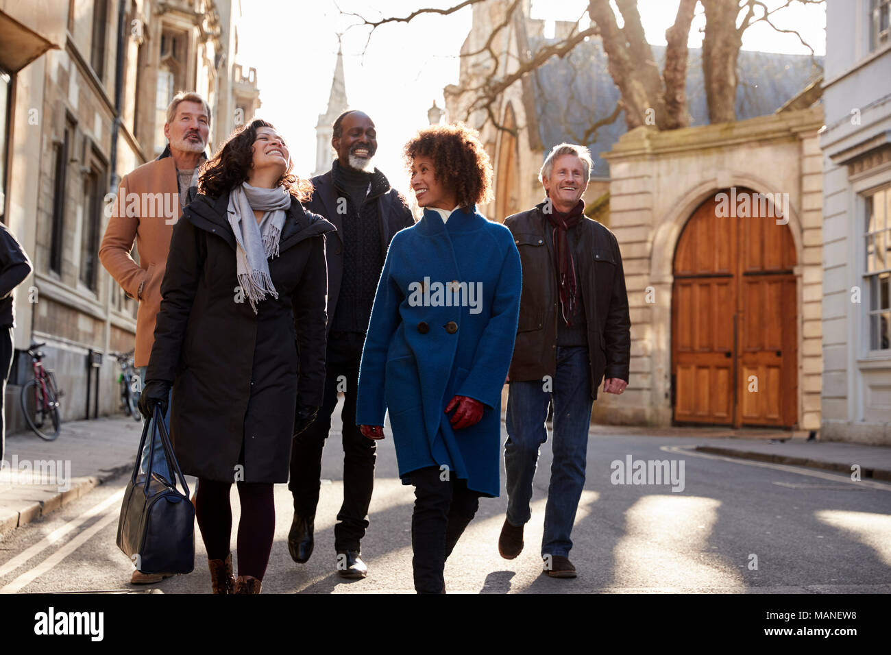 Group Of Mature Friends Walking Through City In Fall Together Stock Photo