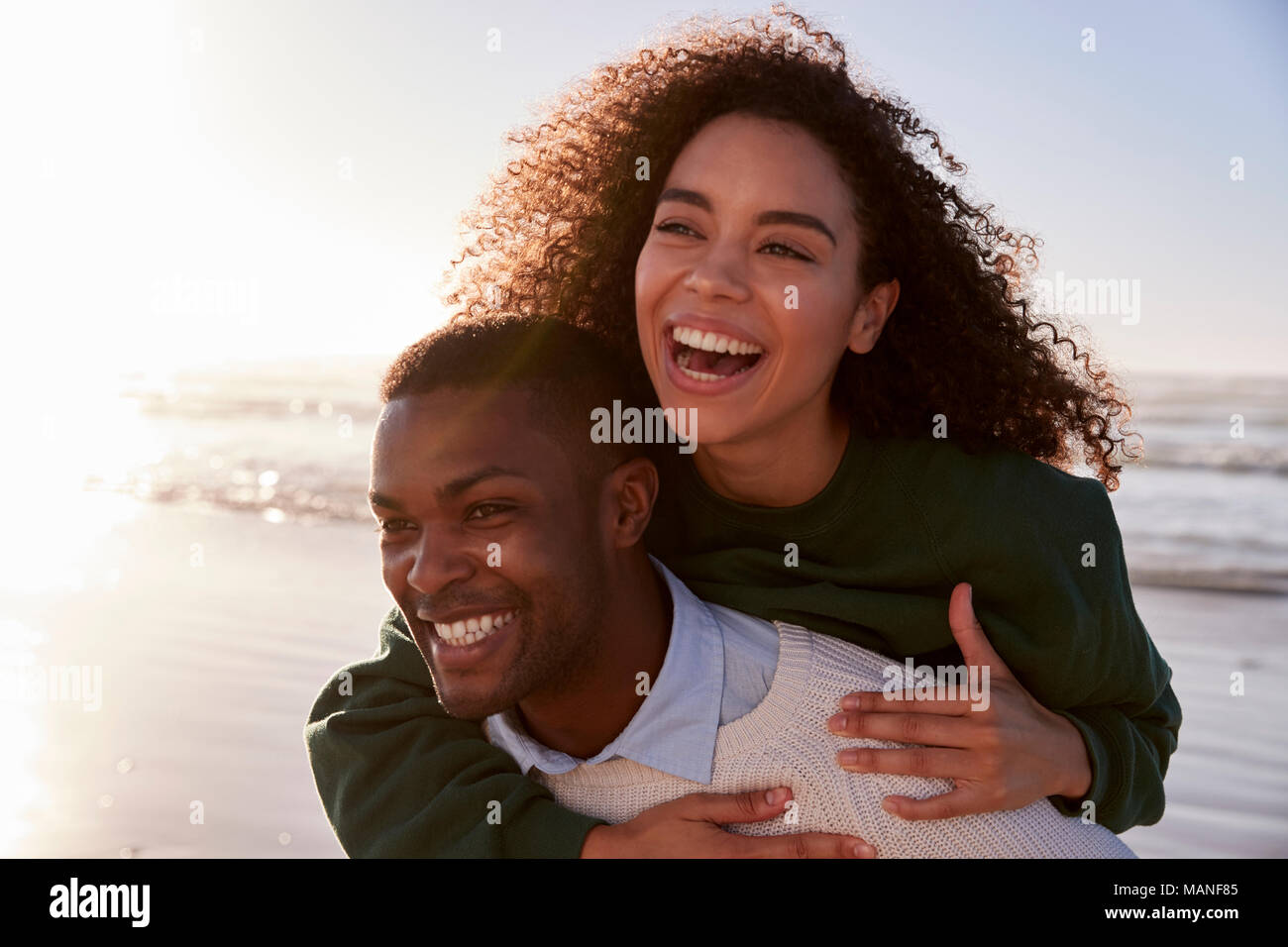 Man Giving Woman Piggyback On Winter Beach Vacation Stock Photo