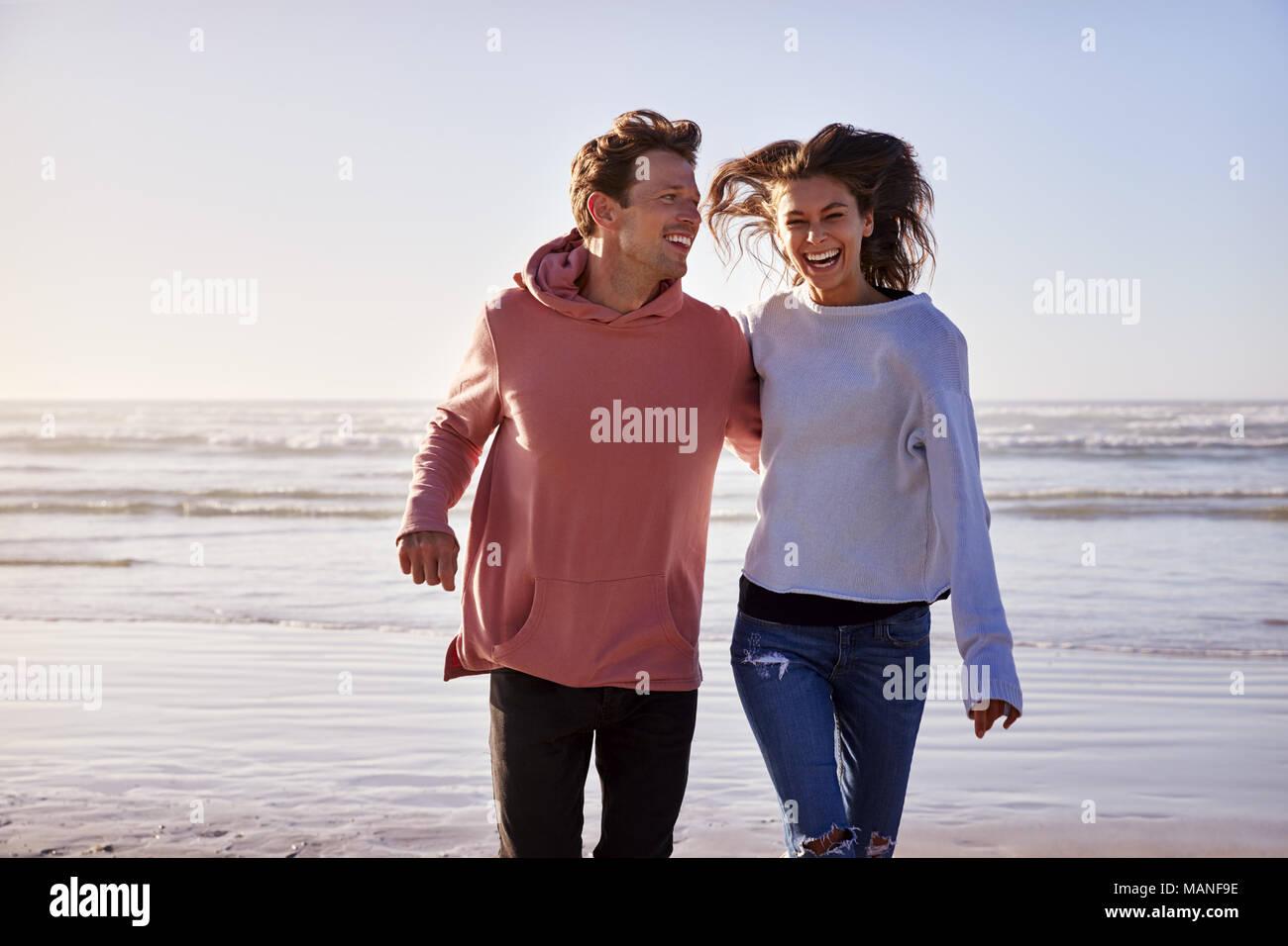 Couple Having Fun Running Along Winter Beach Together Stock Photo
