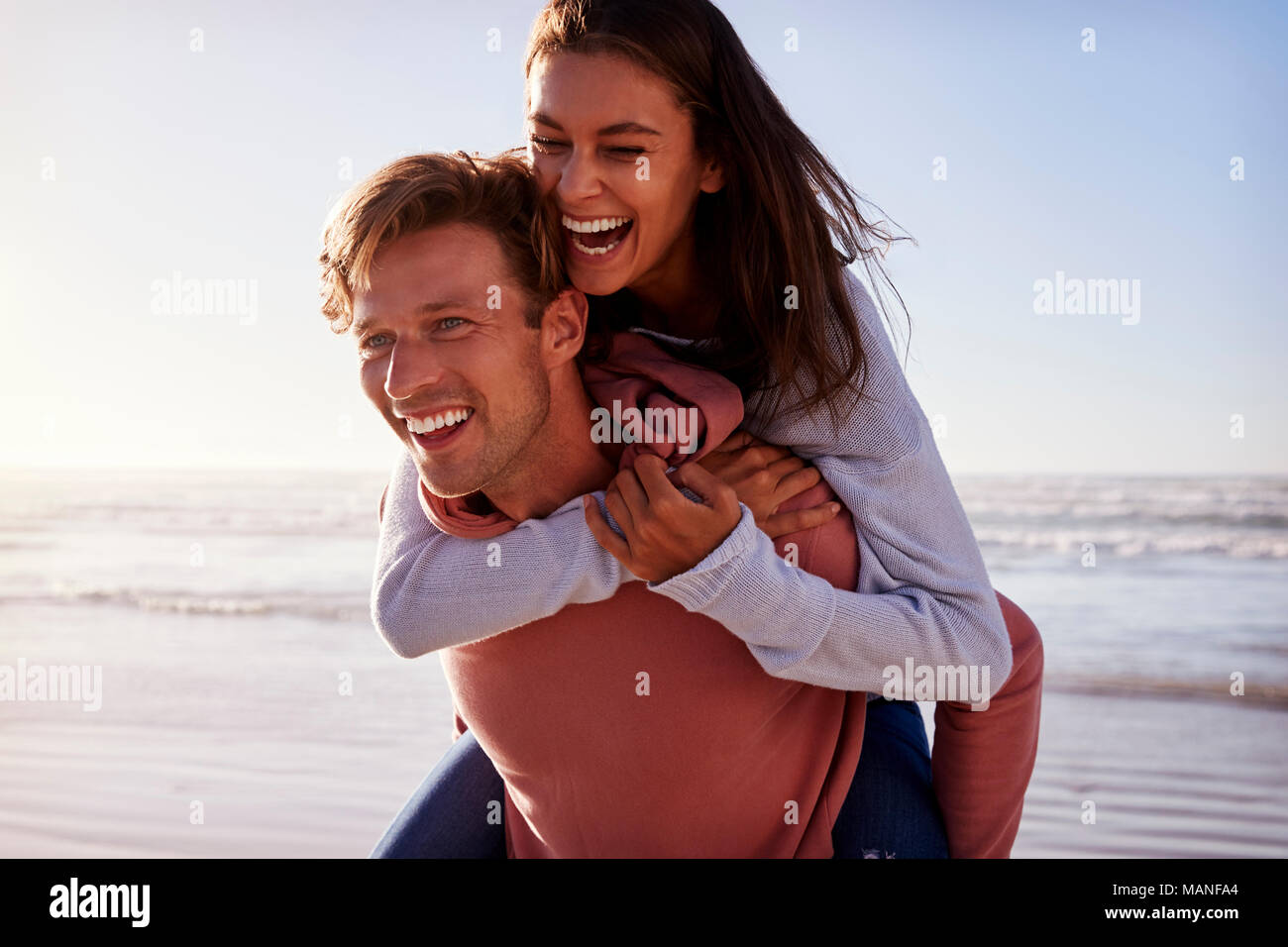 Man Giving Woman Piggyback On Winter Beach Vacation Stock Photo