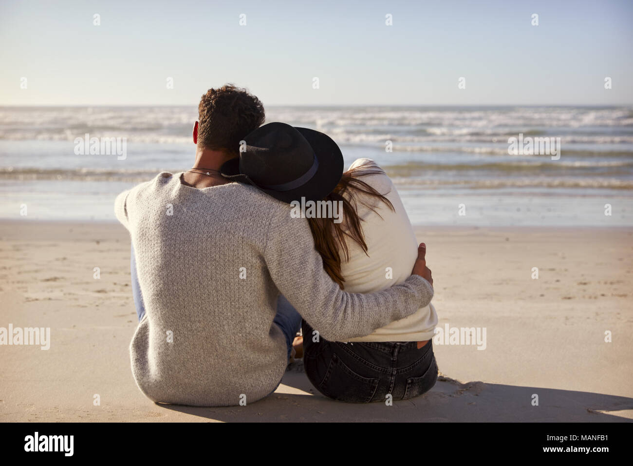 Romantic Couple Sitting On Winter Beach Together Stock Photo