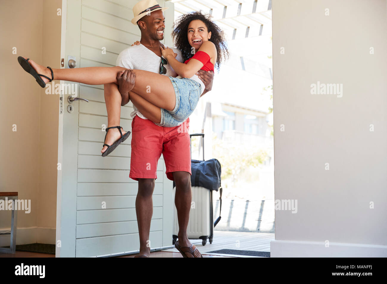 Man Carries Woman Over Threshold Of Honeymoon Rental Stock Photo