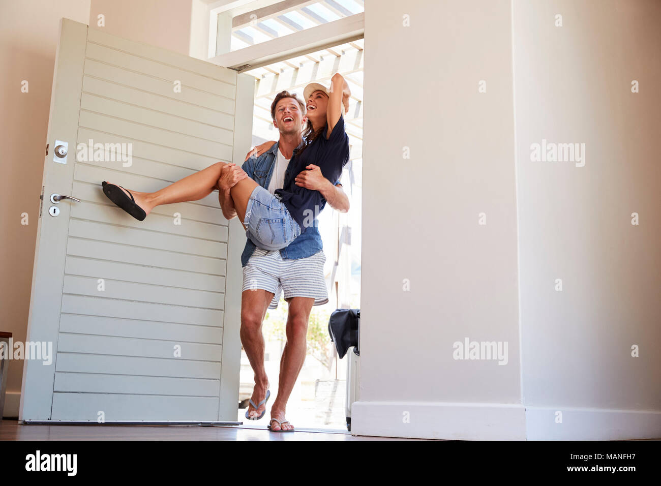 Man Carries Woman Over Threshold Of Honeymoon Rental Stock Photo