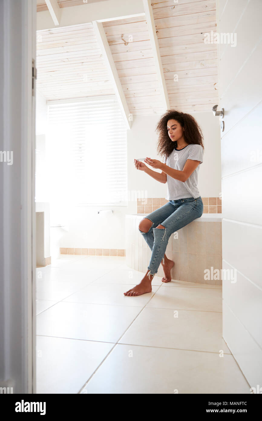 Concerned Woman In Bathroom Using Home Pregnancy Test Stock Photo