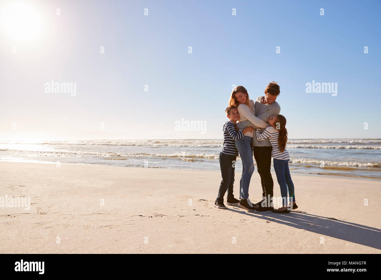 Loving Family Embracing On Winter Beach Stock Photo
