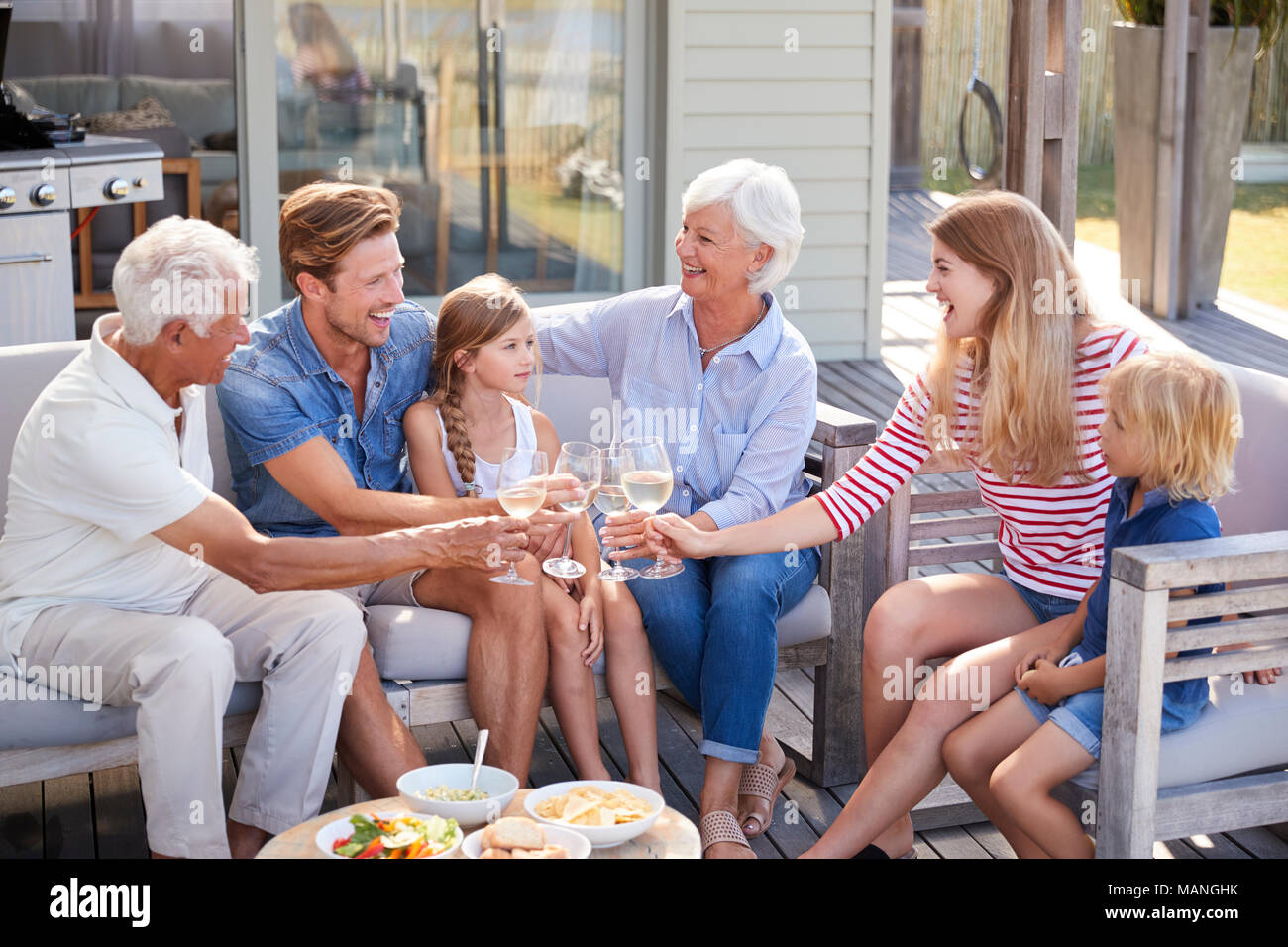 Multi Generation Family Enjoy Outdoor Drinks And Snacks At Home Stock Photo