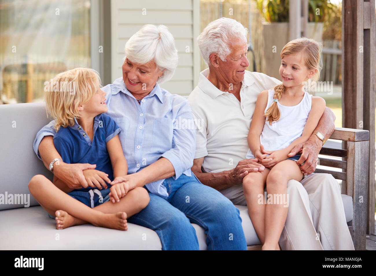 Grandparents With Grandchildren Relaxing On Deck At Home Stock Photo
