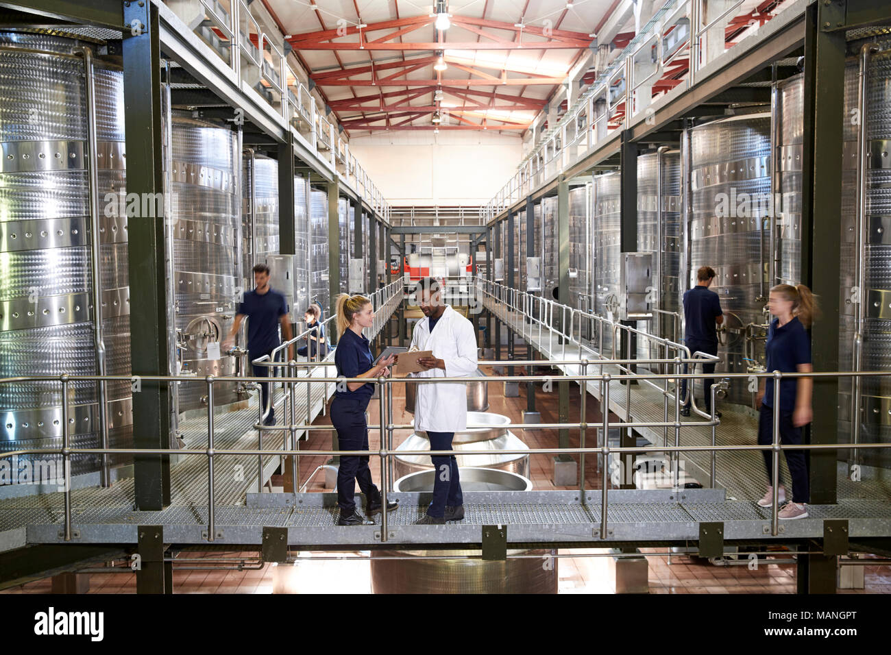 Two staff talking on gangway in a modern winemaking factory Stock Photo