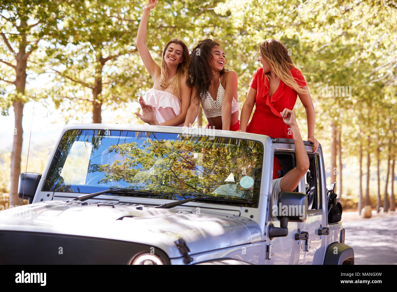 Friends driving on empty road in an open top jeep, close up Stock Photo