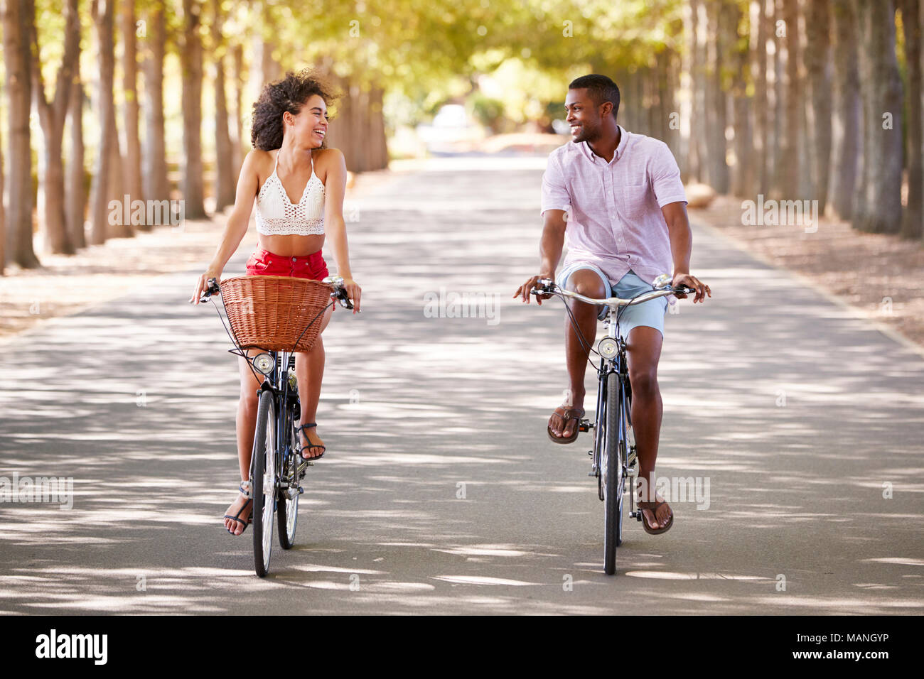 Young mixed race couple riding bicycles looking at each other Stock Photo