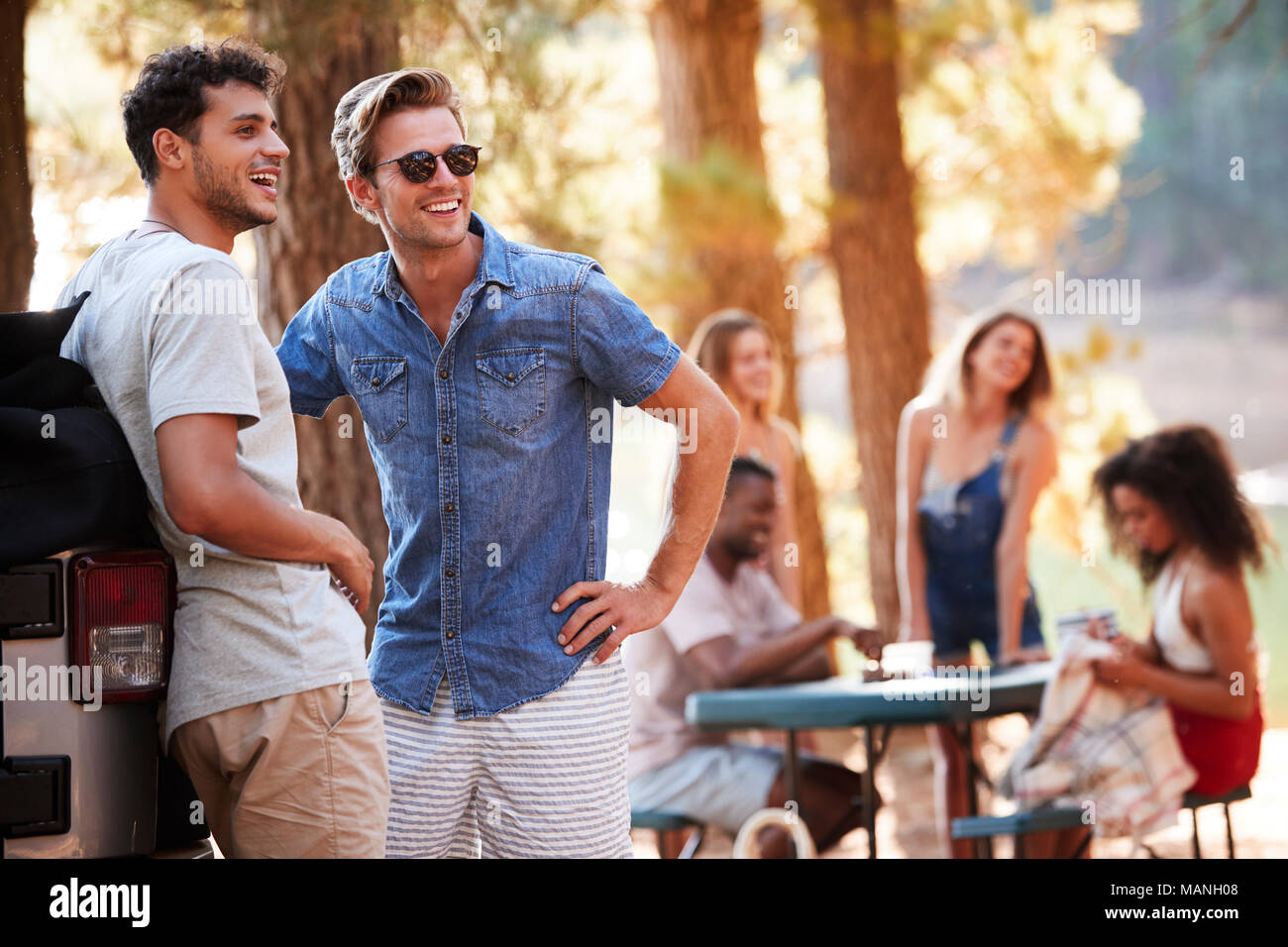 Two young men hanging out with friends by a lake Stock Photo