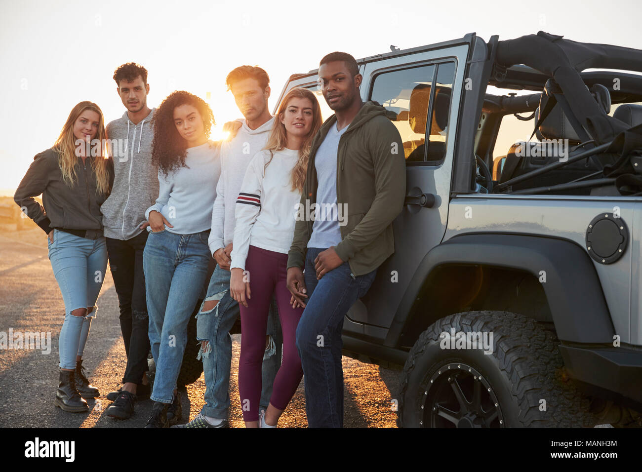 Young adult friends on a road trip standing by their jeep Stock Photo