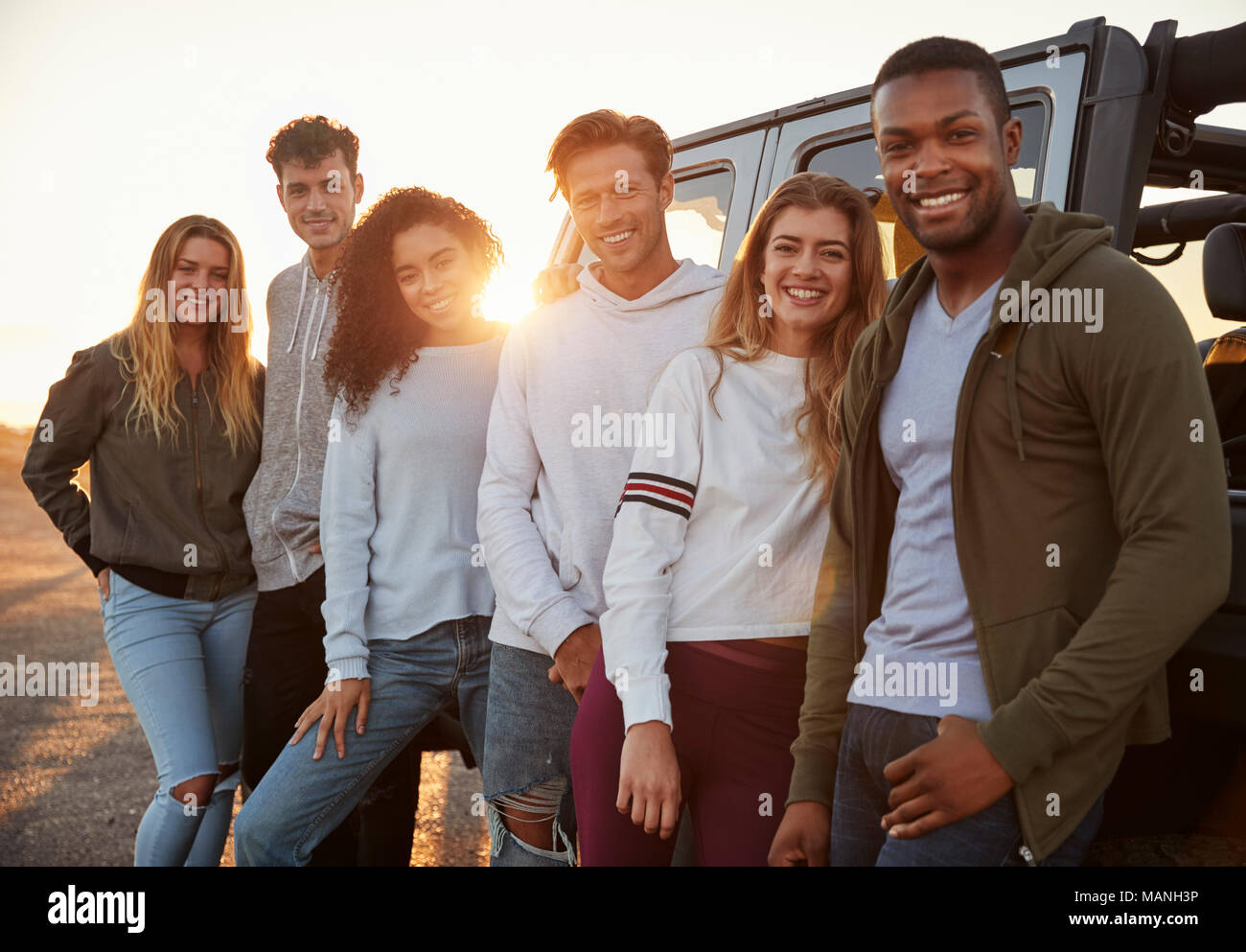 Young adult friends on a road trip standing by jeep, close up Stock Photo